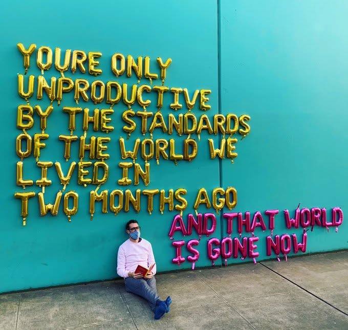 Hombre sentado leyendo junto a un mural con globos de letras