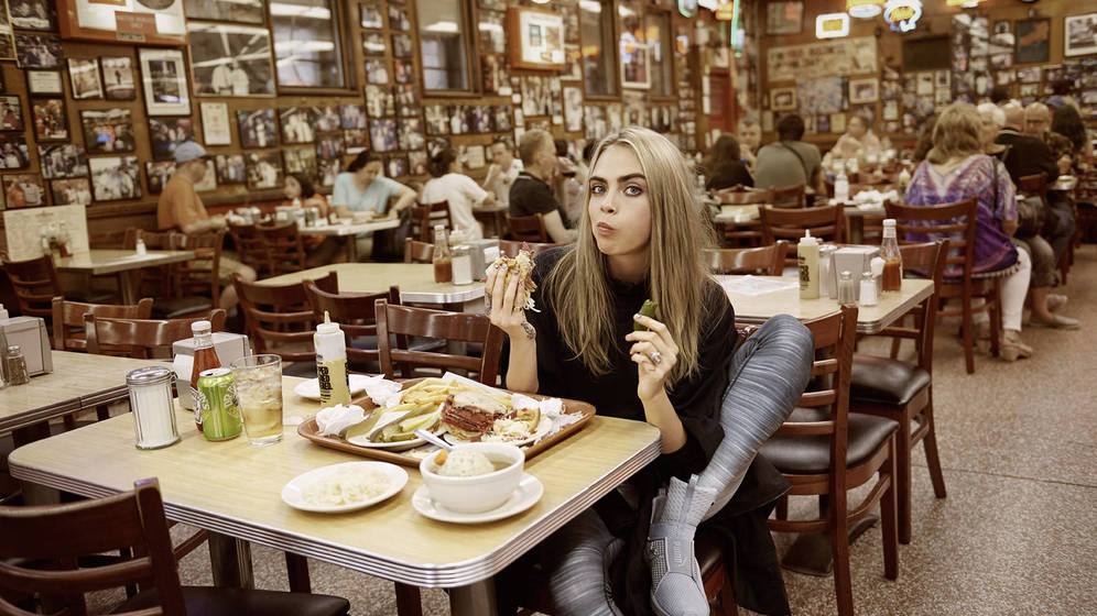 Mujer comiendo un sándwich en un local de delicatessen